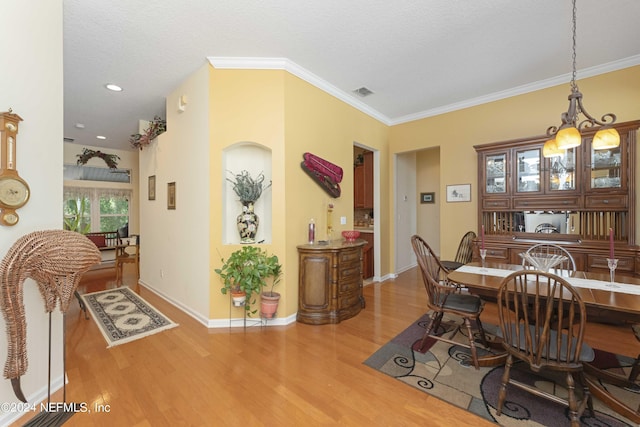 dining room with baseboards, wood finished floors, visible vents, and crown molding