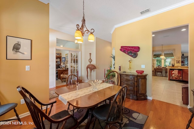 dining space with a textured ceiling, an inviting chandelier, crown molding, and hardwood / wood-style floors