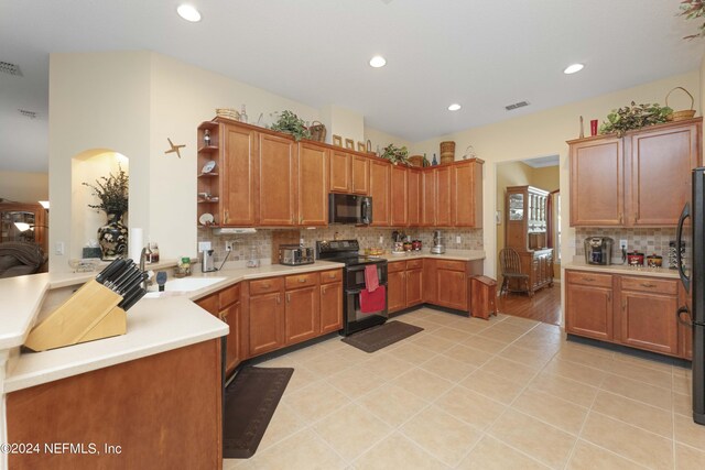 kitchen featuring light wood-type flooring, backsplash, sink, kitchen peninsula, and black appliances