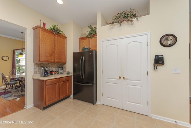 kitchen featuring brown cabinets, freestanding refrigerator, light countertops, and light tile patterned flooring