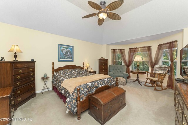 bedroom with ceiling fan, multiple windows, light colored carpet, and lofted ceiling