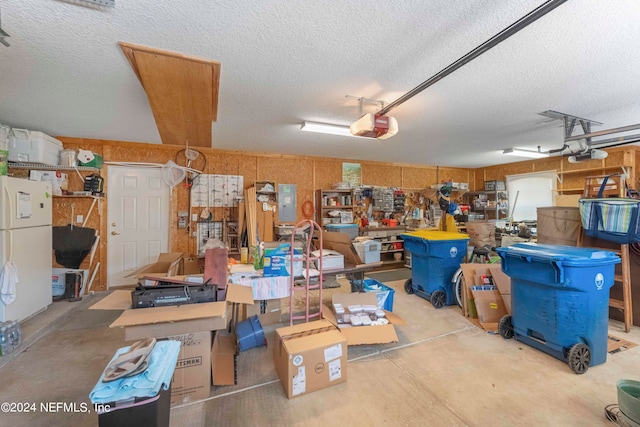 garage with a workshop area, a garage door opener, and white fridge