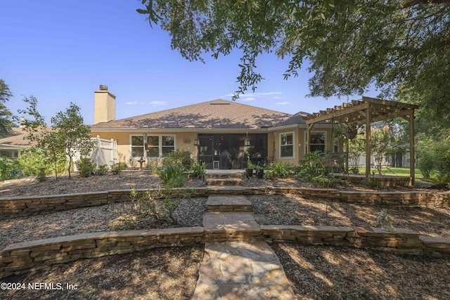 view of front of house with a pergola, fence, a sunroom, stucco siding, and a chimney