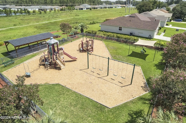 view of home's community featuring playground community, a lawn, and fence