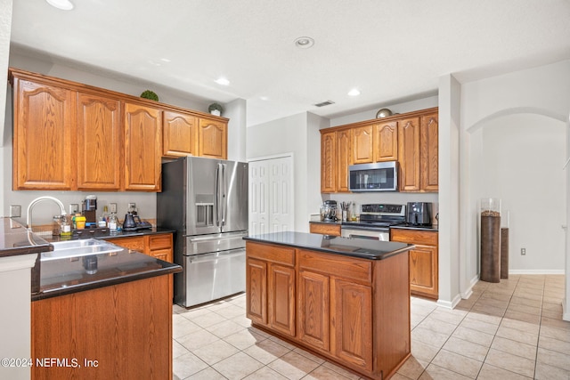 kitchen with a center island, light tile patterned flooring, stainless steel appliances, and sink