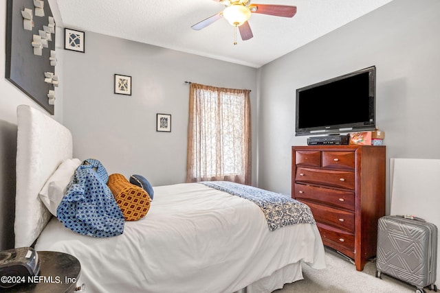 bedroom featuring ceiling fan, light colored carpet, and a textured ceiling