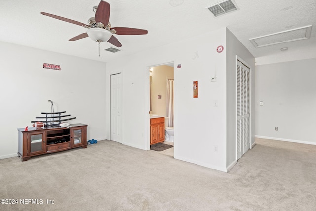 living room featuring light carpet, ceiling fan, and a textured ceiling