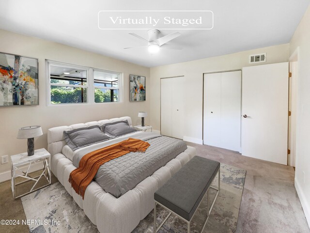 carpeted bedroom with ceiling fan and multiple closets