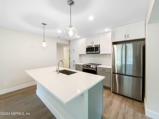 kitchen with tasteful backsplash, sink, stainless steel appliances, and light hardwood / wood-style flooring