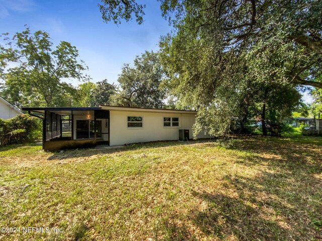 rear view of property featuring central air condition unit, a sunroom, and a yard