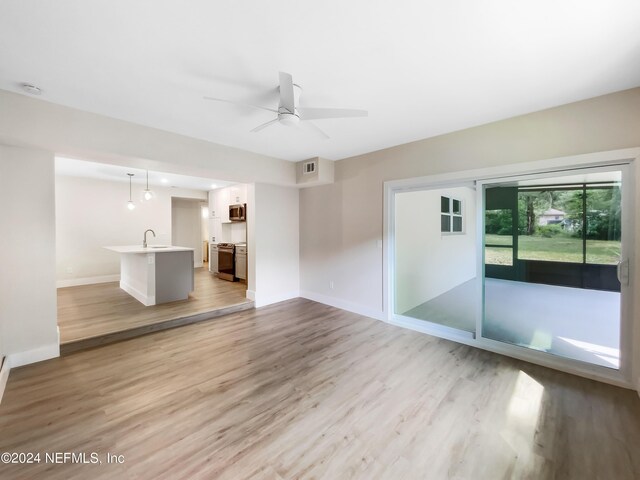 unfurnished living room with ceiling fan, sink, and light hardwood / wood-style floors