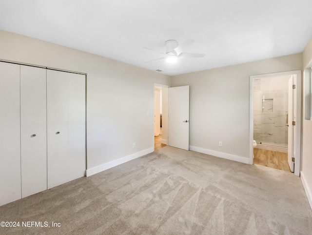 unfurnished bedroom with ensuite bathroom, a closet, and light colored carpet