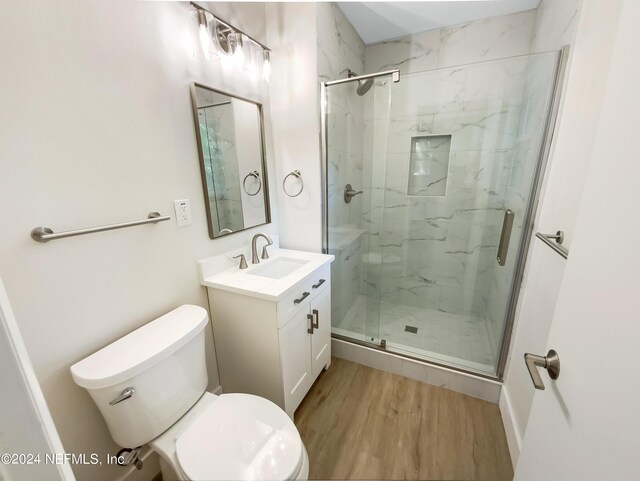 bathroom with a shower with shower door, vanity, wood-type flooring, and toilet