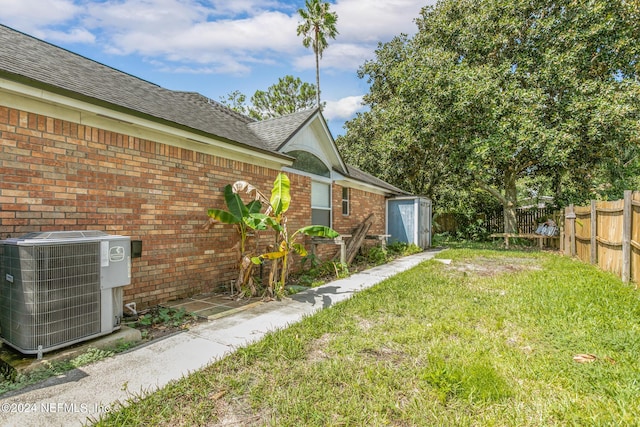 view of yard with an outbuilding, central AC, a storage shed, and fence