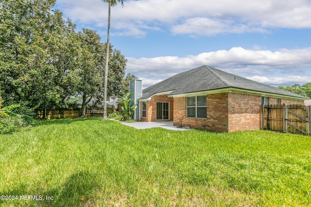 back of property with a fenced backyard, brick siding, a lawn, a chimney, and a patio area