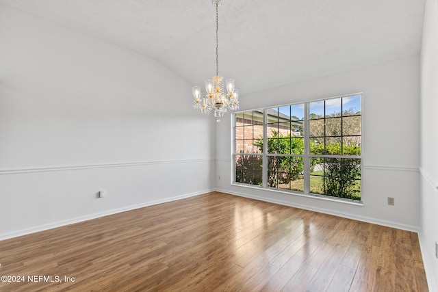 unfurnished dining area with lofted ceiling, baseboards, wood finished floors, and a notable chandelier