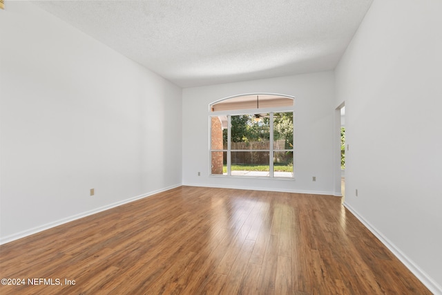 spare room featuring a textured ceiling, baseboards, and wood finished floors