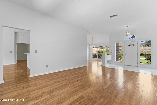 unfurnished living room with a chandelier, visible vents, and light wood-style floors