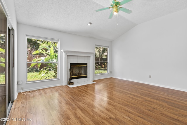 unfurnished living room featuring baseboards, lofted ceiling, wood finished floors, a textured ceiling, and a fireplace