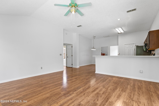 unfurnished living room with ceiling fan, a textured ceiling, visible vents, vaulted ceiling, and light wood-type flooring