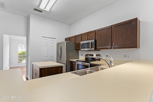 kitchen featuring dark brown cabinetry, a kitchen island, visible vents, light countertops, and appliances with stainless steel finishes