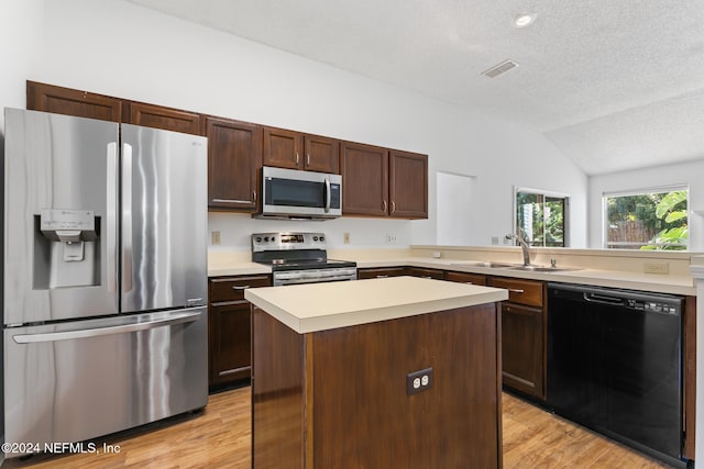 kitchen with lofted ceiling, light wood-style flooring, a sink, light countertops, and appliances with stainless steel finishes