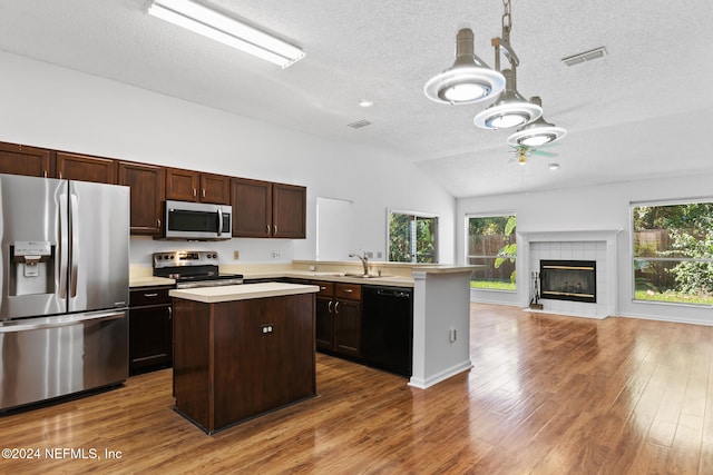 kitchen with a peninsula, wood finished floors, visible vents, light countertops, and appliances with stainless steel finishes