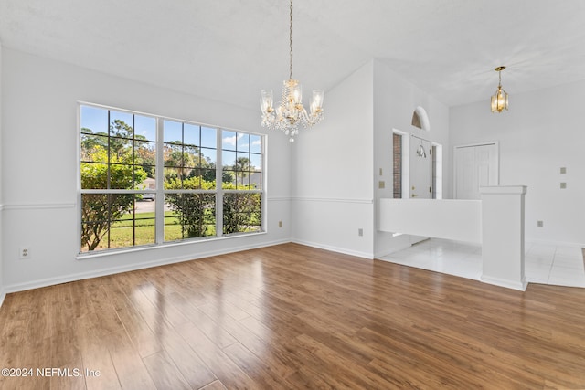 unfurnished dining area with baseboards, a chandelier, and wood finished floors