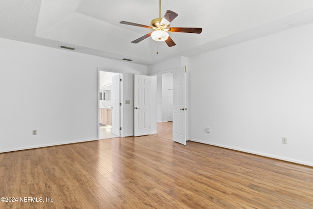 unfurnished bedroom featuring light wood-style flooring, ensuite bath, visible vents, and baseboards