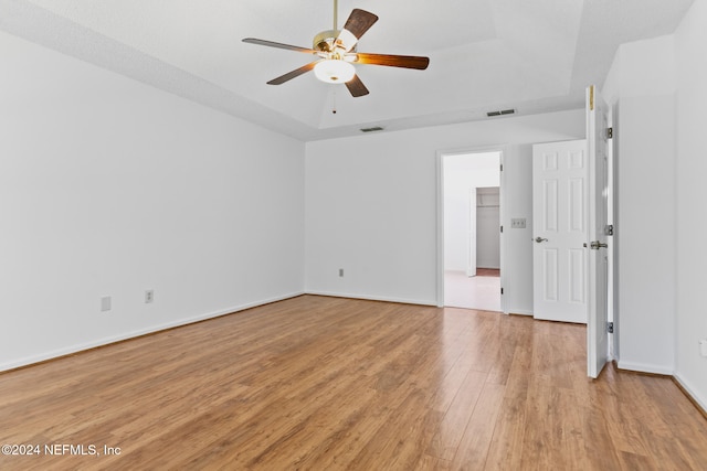 spare room featuring visible vents, baseboards, a raised ceiling, a ceiling fan, and light wood-type flooring