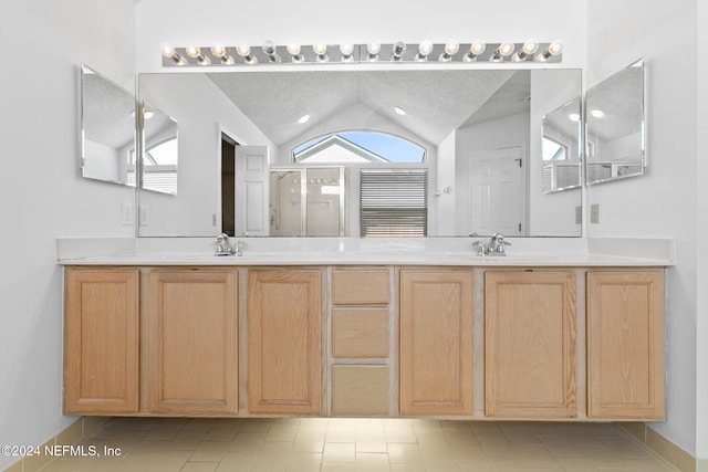 bathroom featuring double vanity, a stall shower, lofted ceiling, a textured ceiling, and a sink