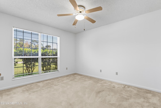 carpeted spare room with a textured ceiling, ceiling fan, and baseboards