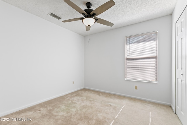 carpeted spare room featuring visible vents, a textured ceiling, and baseboards