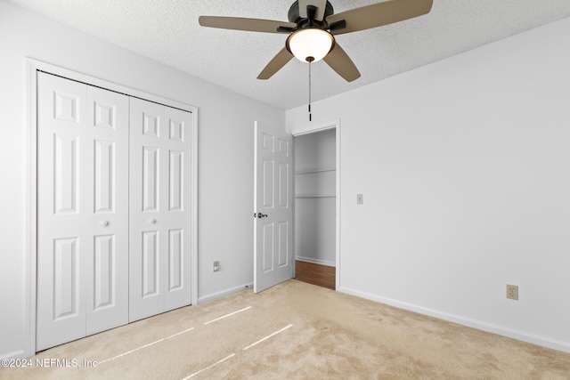 unfurnished bedroom featuring a closet, a textured ceiling, baseboards, and carpet flooring