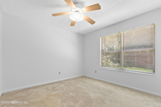 empty room with ceiling fan, baseboards, a textured ceiling, and light colored carpet