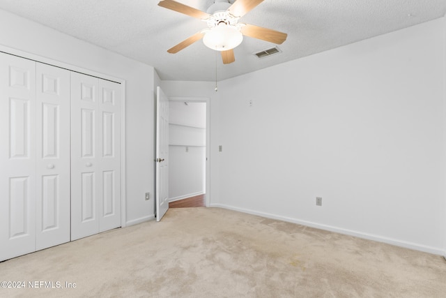 unfurnished bedroom with carpet, a textured ceiling, visible vents, and a closet