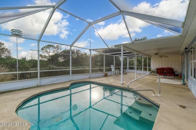 view of swimming pool with ceiling fan, glass enclosure, and a patio area