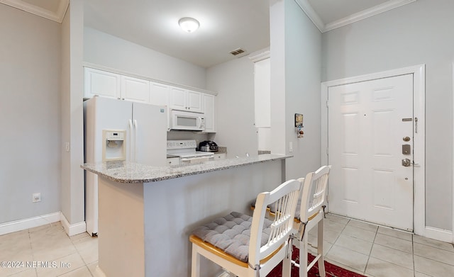 kitchen with white appliances, light tile patterned flooring, light stone counters, white cabinets, and kitchen peninsula