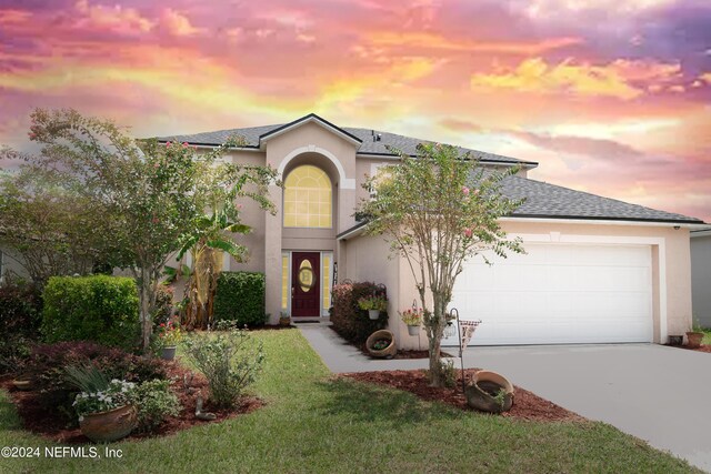 view of front of home with a garage and a yard