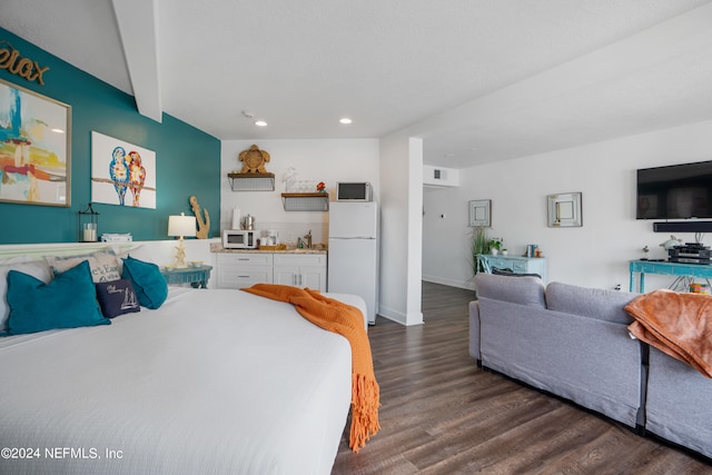 bedroom with sink, beam ceiling, white refrigerator, and dark hardwood / wood-style floors