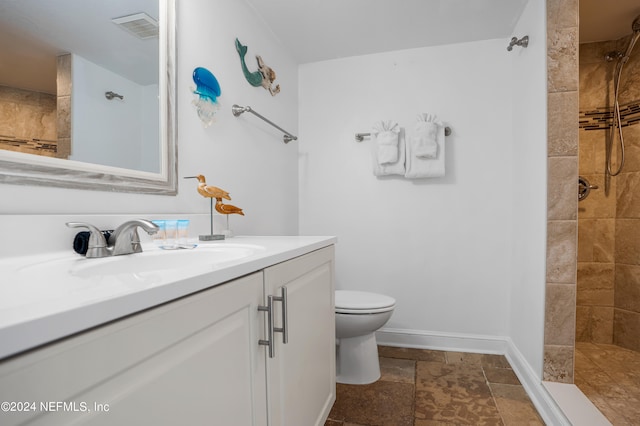 bathroom with tiled shower, tile patterned floors, toilet, and vanity