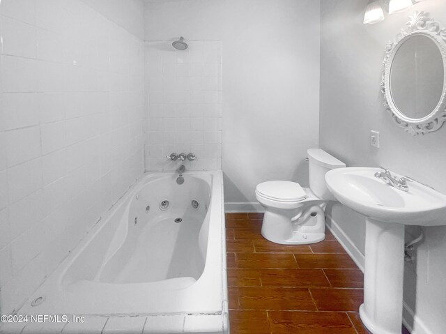 bathroom with tiled shower / bath combo, toilet, and hardwood / wood-style floors