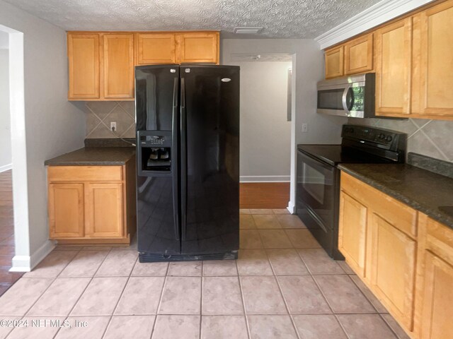 kitchen with decorative backsplash, light tile patterned flooring, a textured ceiling, and black appliances