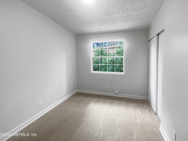 carpeted spare room featuring a textured ceiling