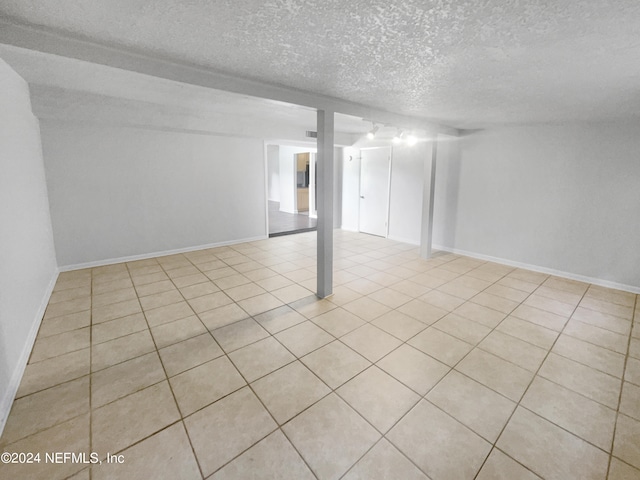 tiled empty room featuring a textured ceiling