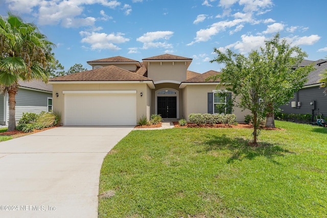 mediterranean / spanish home with a garage and a front lawn