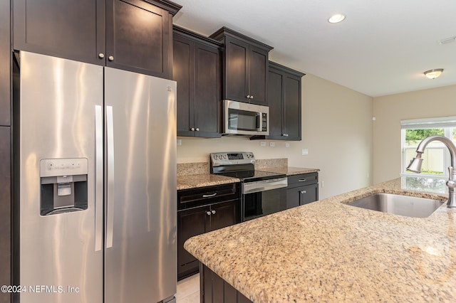 kitchen featuring sink, dark brown cabinets, light stone countertops, and appliances with stainless steel finishes