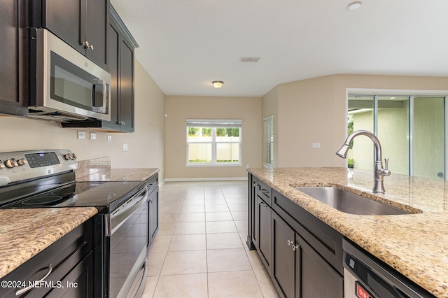 kitchen featuring light stone counters, dark brown cabinetry, light tile patterned floors, stainless steel appliances, and sink