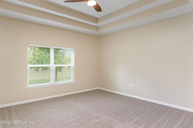 carpeted empty room featuring ceiling fan and a tray ceiling