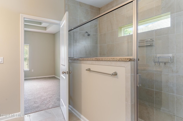 bathroom featuring tile patterned floors, a healthy amount of sunlight, and a shower with shower door